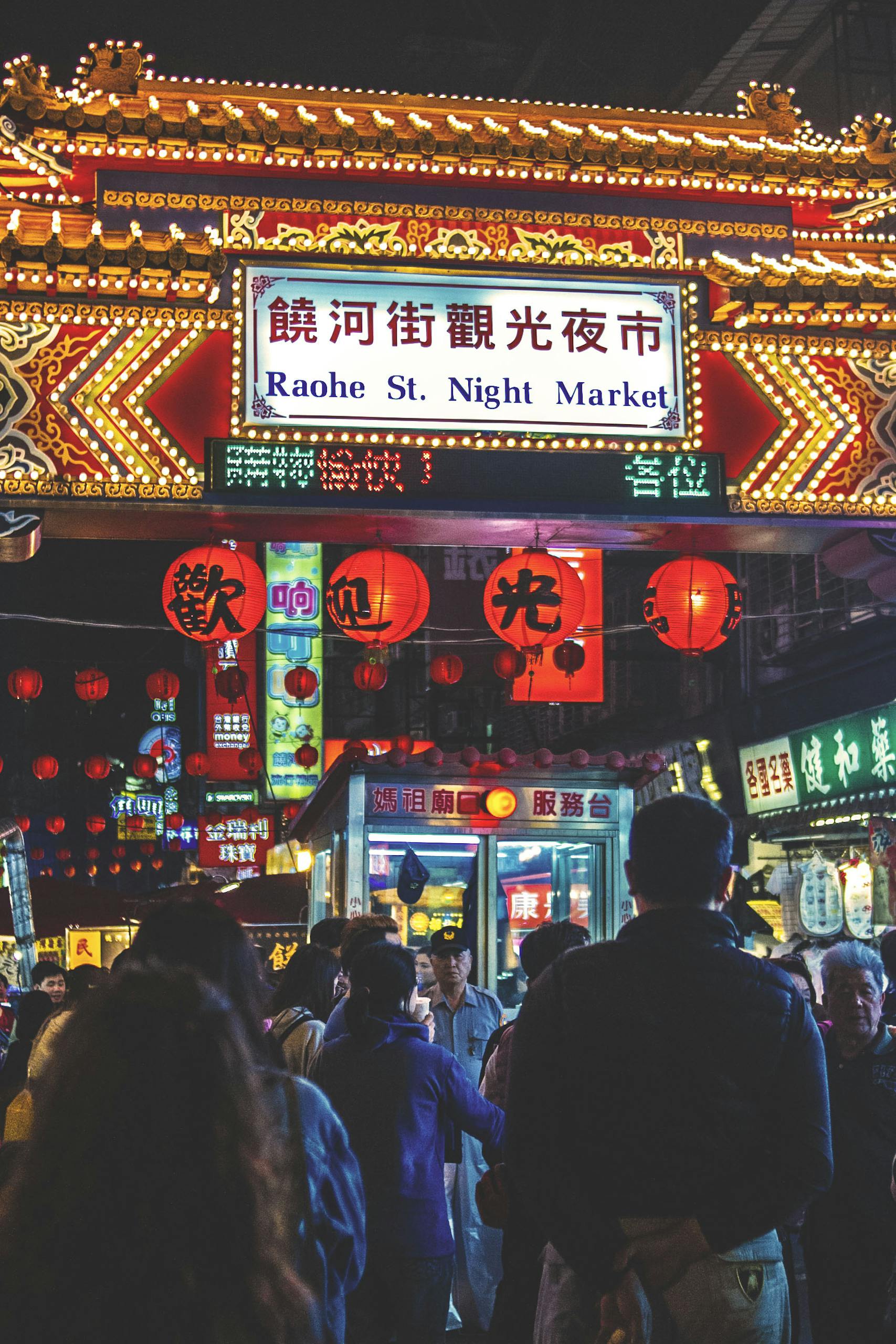 Vibrant crowd and neon signs at the lively Raohe Street Night Market, Taipei.